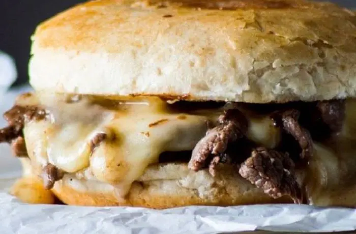 Sándwich Barros Luco chileno en pan marraqueta, con churrascos de res sellados y abundante queso fundido chorreando por los costados.
