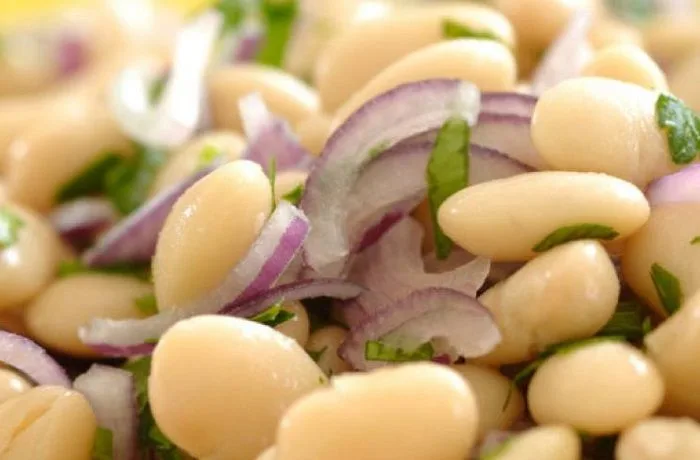 Ensalada de porotos con cebolla y cilantro en un plato de madera, lista para servir
