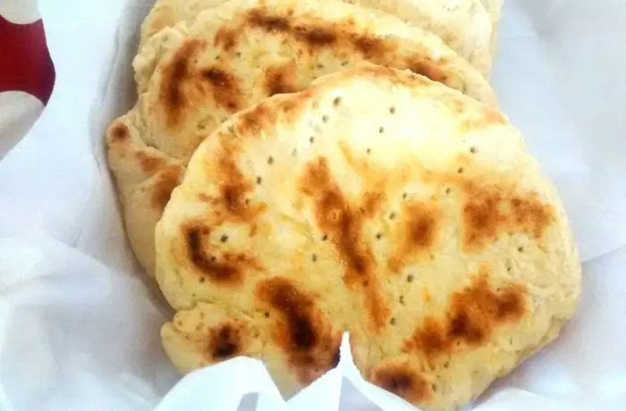 Churrascas chilenas recién cocinadas en sartén, doradas y planas, apiladas sobre una tabla.