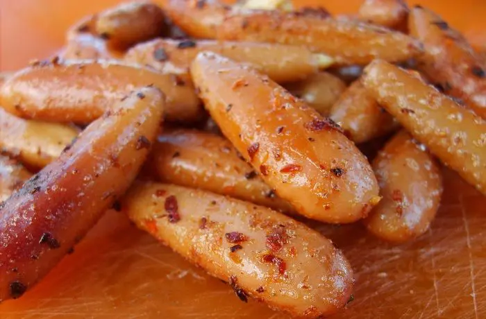 Piñones de araucaria salteados con merkén y ajo en una sartén, listos para servir.