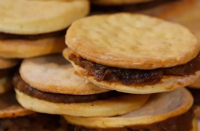 Alfajores de chancaca Alfajores de chancaca chilenos rellenos, mostrando la hojarasca y el relleno oscuro de chancaca, nueces y pasas.