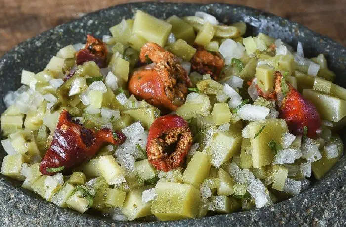 Receta de ensalada de piures y ulte Plato de ensalada de piures rojos y trozos de ulte verde oliva, mezclados con cebolla blanca, cilantro y ají verde.