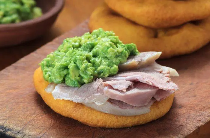 Pernil de chancho con palta en sopaipillas Sándwich de pernil de cerdo laminado con una capa generosa de palta molida entre dos sopaipillas doradas.