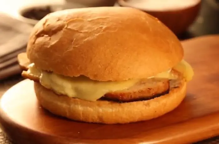 Sándwich diplomático chileno Un sándwich diplomático chileno en pan frica con abundante lomo de cerdo y queso chanco derretido desbordando por los lados.