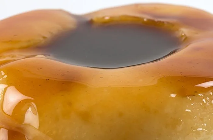 Postre Macho Ruso chileno desmoldado, con caramelo líquido escurriendo y servido en un plato, mostrando su textura suave y cremosa.