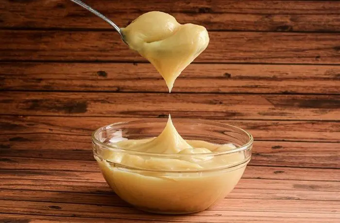 Manjar casero chileno o dulce de leche, de color caramelo oscuro, servido en un tazón de vidrio.