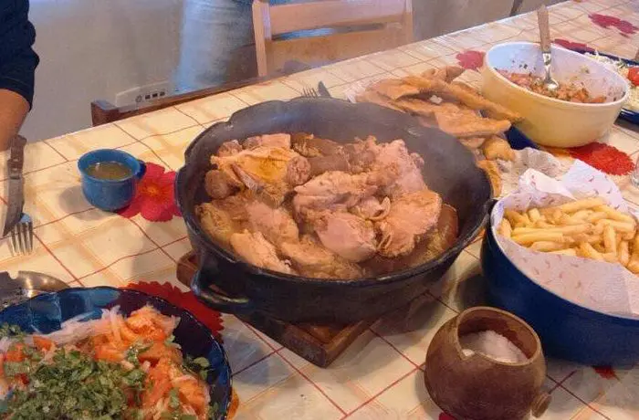 Guiso Pollona de Los Ángeles en una olla de greda, con pollo, longanizas y costillar ahumado, listo para servir.