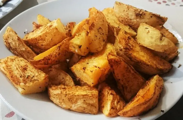 Papas rústicas al horno Bandeja de papas rústicas al horno con piel, doradas y condimentadas con orégano y merkén.