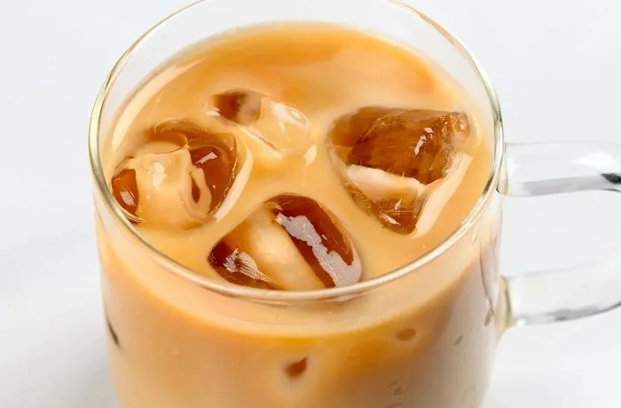 Receta de café helado Starbucks Un vaso de cristal con hielos, café espresso y una capa superior de espuma de leche blanca, estilo Iced Latte.