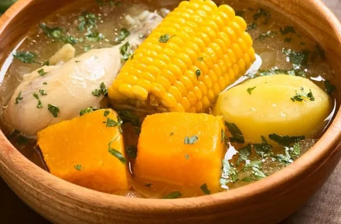 Receta de cazuela de pollo o ave: Guiso tradicional del campo chileno 1 Cazuela de pollo chilena servida en un plato de greda, con presa de pollo, choclo, papa y zapallo, espolvoreada con cilantro.