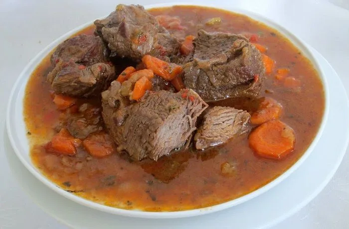 Carne al jugo chilena Plato de carne al jugo chilena, con salsa espesa y trozos de carne blanda en un plato hondo