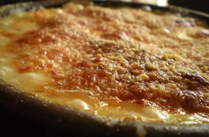 Chupe de jibia chileno gratinado con queso parmesano, servido en pocillos de greda.