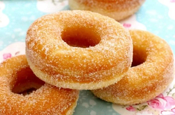 Donas caseras Donas caseras (donuts) con glaseado de vainilla y mostacillas de colores, servidas sobre una rejilla.
