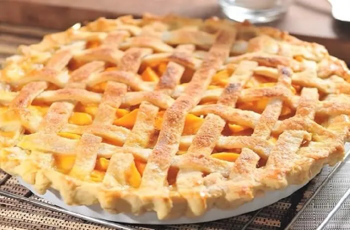 Receta de kuchen de duraznos chileno: Clásico de las onces del sur 1 Kuchen de durazno recién horneado, con una base de masa, crema pastelera, y gajos de durazno caramelizados.