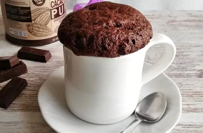 Queque en taza (mug cake) de chocolate, listo y caliente, recién sacado del microondas.