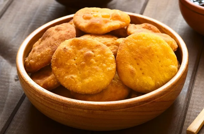 Sopaipillas circulares sin gluten, doradas y crujientes, servidas en una fuente de madera rústica.