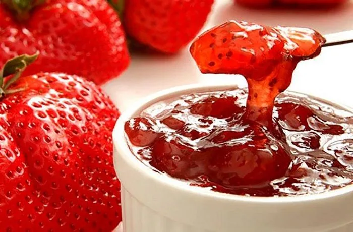 Mermelada de frutillas casera, servida en un plato con bayas frescas.