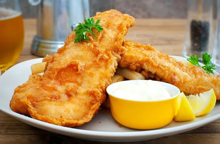 Receta de batido para pescado frito: ¿Cómo obtener una corteza crujiente perfecta? 1 Batido de harina y cerveza para pescado frito, de consistencia cremosa, en un bol de vidrio.
