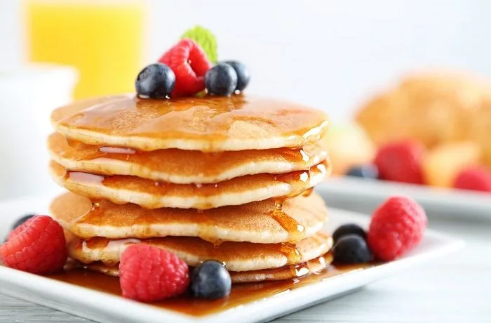 Receta de hot cakes de avena: Caseros, esponjosos y deliciosos 1 Pila de hot cakes esponjosos de avena con plátano y miel de maple, desayuno saludable