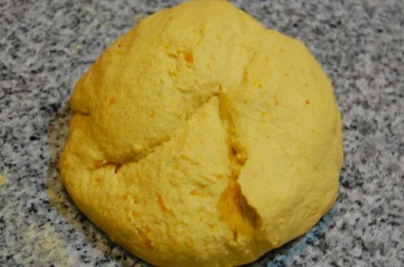Una masa de color naranja suave, lisa y elástica, lista para ser estirada.