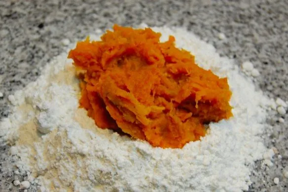 Harina de trigo dispuesta en un bol mezclada con puré de zapallo amarillo intenso.