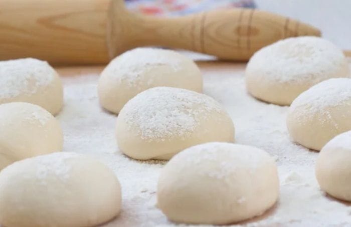 Bollos de pan amasado ya formados, pinchados con tenedor y listos para hornear 