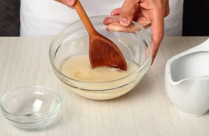Disolver levadura en agua tibia Levadura seca disolviéndose en agua tibia con una cuchara de madera