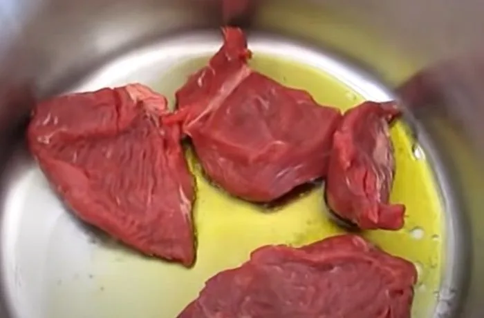 Dorando la carne Trozos de carne de vacuno dorándose en una olla con aceite, un paso crucial para sellar los jugos.
