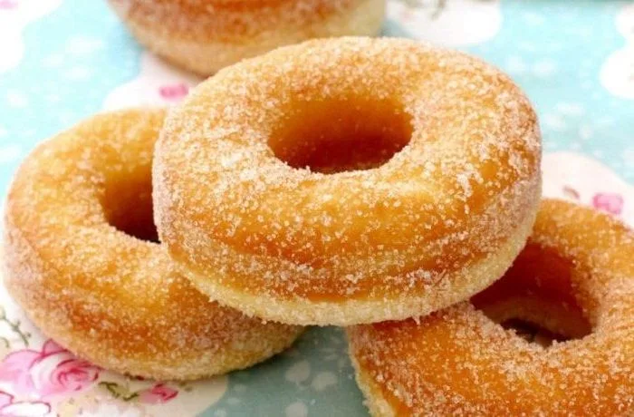 Receta de roscas fritas o rosquillas: Perfectas para cualquier momento 1 Fuente con roscas fritas chilenas doradas, cubiertas con azúcar granulada y listas para servir.