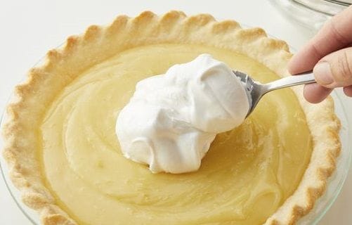 Pie de limón siendo decorado con el merengue en la superficie antes de dorar Exportar a Hojas de cálculo 