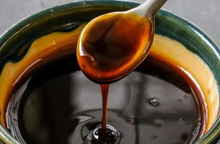 ¿Cómo hacer salsa teriyaki casera y fácil? Receta japonesa tradicional para 6 personas 1 Salsa teriyaki japonesa de color oscuro y textura viscosa, servida en un cuenco pequeño de cerámica con semillas de sésamo por encima.