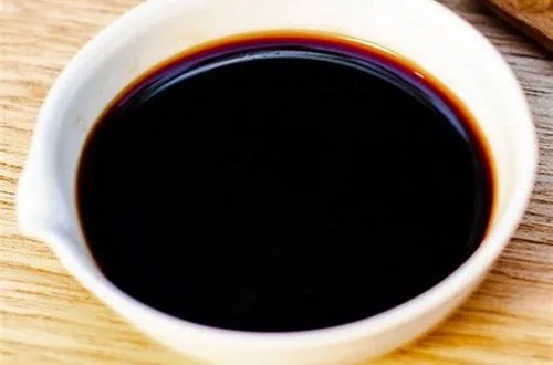 Salsa de soya Botella de salsa de soya oscura vertiéndose en una olla, mostrando su color intenso y opaco.