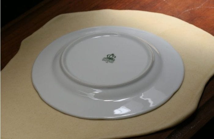 Cortar masa para dobladitas con un plato Cortando la masa estirada en forma de círculo utilizando un plato como guía.