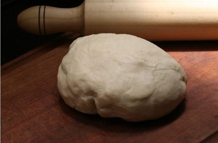 Masa para dobladitas Masa de dobladitas suave y homogénea en un bol, lista para reposar y estirar.