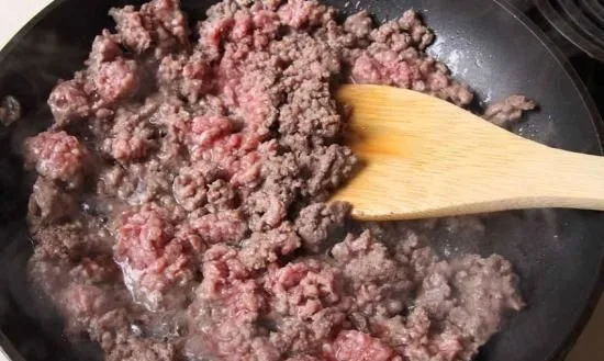Carne molida Carne de vacuno molida sellándose en una sartén, la base proteica para la salsa boloñesa.