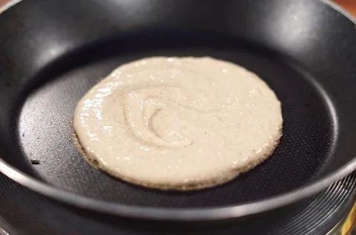 Cocción panqueques Un panqueque de avena dorándose en una sartén antiadherente, mostrando pequeñas burbujas en su superficie.