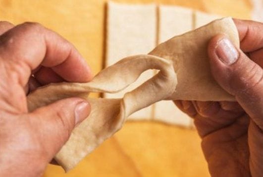 Doblando la masa para darle la forma tradicional de los calzones rotos chilenos