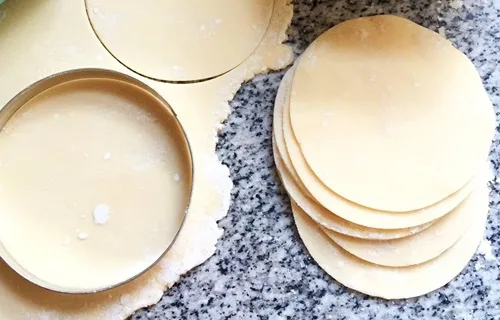 Discos de masa para empanadas dispuestos sobre una superficie enharinada.