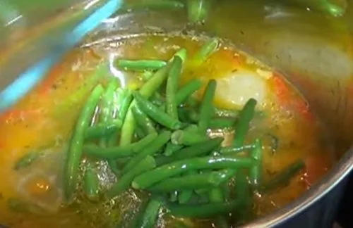 Cocción de la cazuela de ave Cazuela de pollo hirviendo en una olla grande, mostrando el pollo, papas y trozos de choclo.