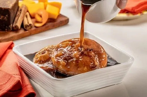 Bañar sopaipillas Sopaipillas fritas siendo sumergidas en una olla con almíbar de chancaca hirviendo.