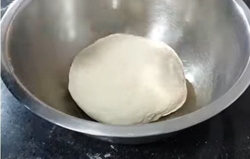 Masa para marraqueta Una bola de masa lisa y elástica reposando en un bol, duplicando su volumen inicial.