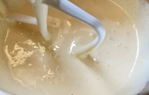 Un bol de vidrio mostrando la mezcla cremosa de huevos, mantequilla y azúcar, base para el bizcocho aireado.
