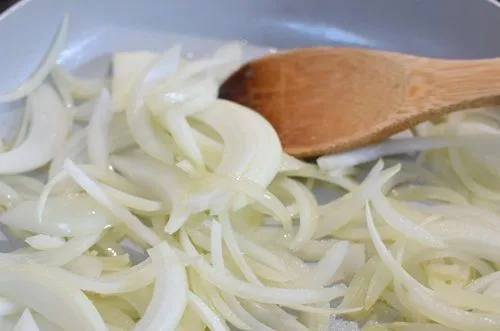 Cocción cebollas Cebolla y morrón cortados en pluma salteándose en aceite para el sofrito del caldo.