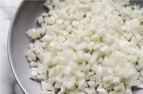 Cebolla blanca finamente picada en cubos pequeños lista para el sofrito.