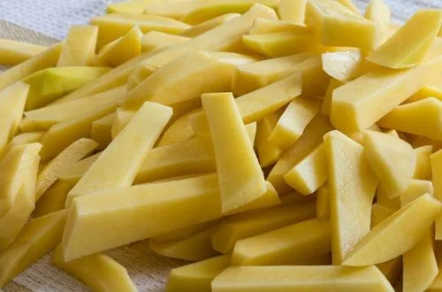 Papas cortadas uniformemente en bastones, listas para ser sumergidas en aceite caliente.