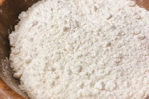 Harina de trigo cernida en un bol grande, lista para mezclar con sal y polvos de hornear.