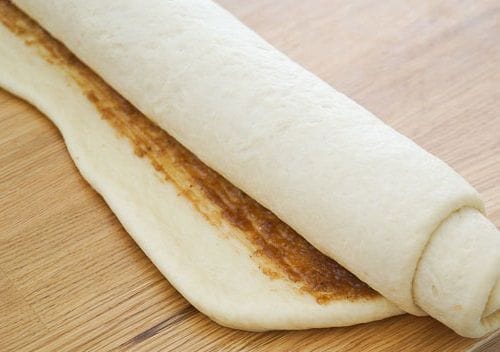 Masa de rollos de canela Un gran rectángulo de masa extendido, cubierto uniformemente con una pasta de azúcar rubia y canela antes de ser enrollado.