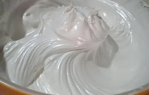Merengue suizo blanco y brillante con picos firmes en un bol de vidrio.