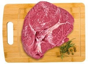 Posta rosada de vacuno Un corte de carne de vacuno fresco y rosado, con fibras finas y poca grasa superficial, listo para ser trozado.