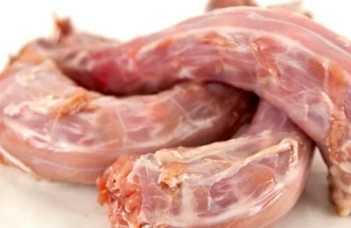 Espinazos de pollo y verduras troceadas en una bandeja de horno, tostados para hacer un caldo concentrado